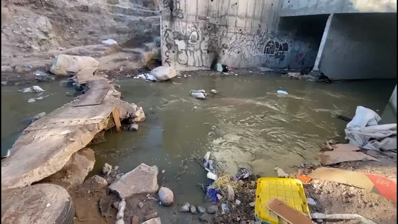 Vecinos piden un puente peatonal cruzan por un arroyo de aguas negras todos los días